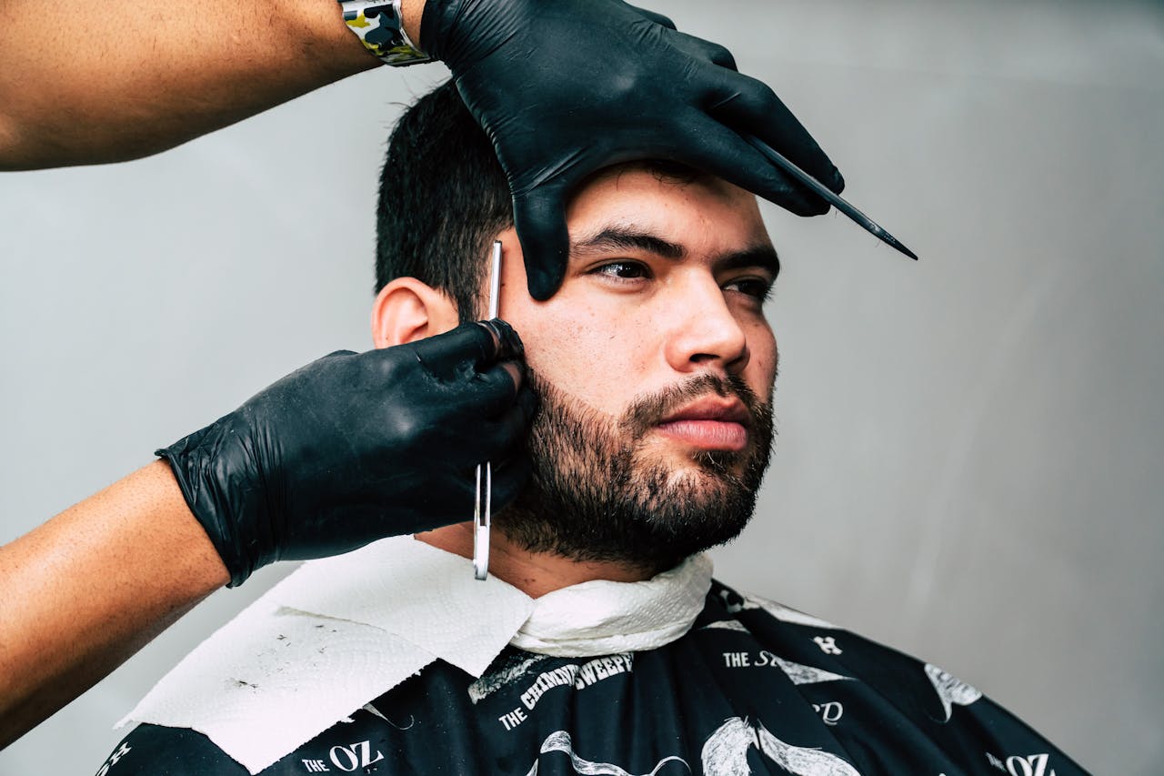 why-choose-us Man receiving a precise beard trim in a barbershop, showcasing expert grooming skills.